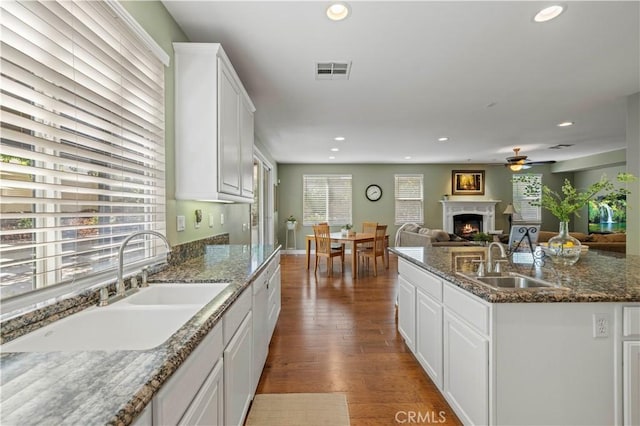 26520 Thackery Ln, Stevenson Ranch, CA 91381 - kitchen featuring a ceiling fan, a warm lit fireplace, recessed lighting, white cabinets, and dark wood-type flooring