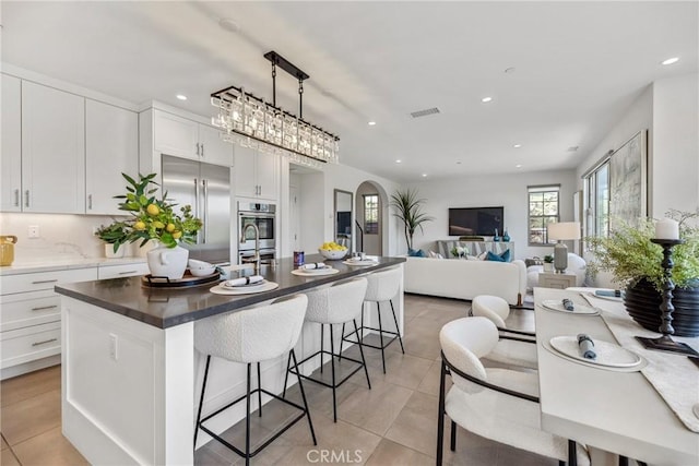 200 Canterbury, Irvine, CA 92618 - kitchen featuring built in refrigerator, light tile patterned floors, a breakfast bar area, a center island with sink, and white cabinetry