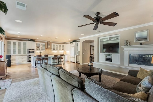 36702 Doreen Dr, Murrieta, CA 92563 - living room featuring light wood-style floors, ornamental molding, arched walkways, ceiling fan, and recessed lighting