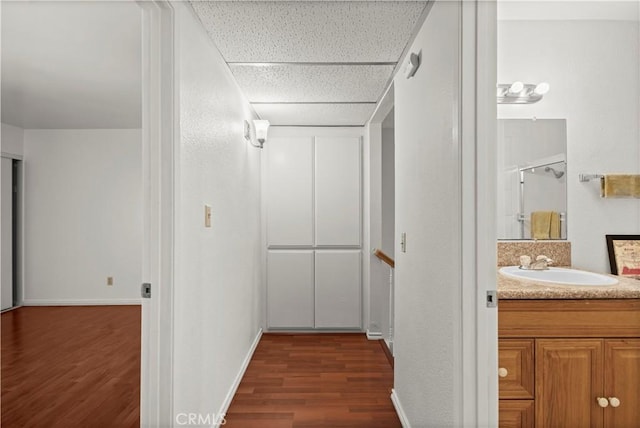 2300 S Hacienda Blvd Unit F8, Hacienda Heights, CA 91745 - hallway featuring a sink, dark wood-style flooring, baseboards, a drop ceiling, and an upstairs landing