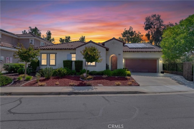 10460 Meadow Lark Ave, Moreno Valley, CA 92557 - mediterranean / spanish-style house featuring an attached garage, a tiled roof, stucco siding, and solar panels