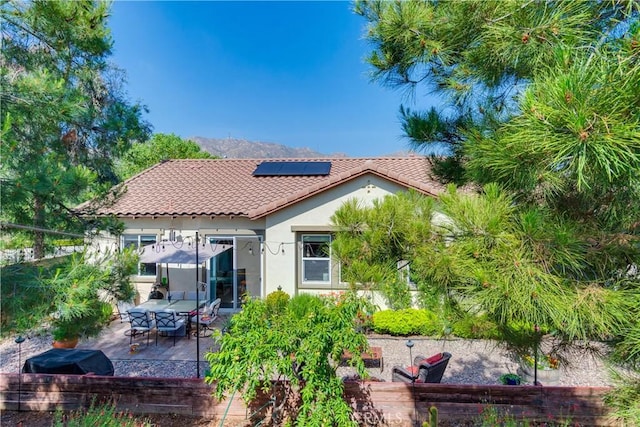 10460 Meadow Lark Ave, Moreno Valley, CA 92557 - back of house with stucco siding, a tiled roof, roof mounted solar panels, and a patio