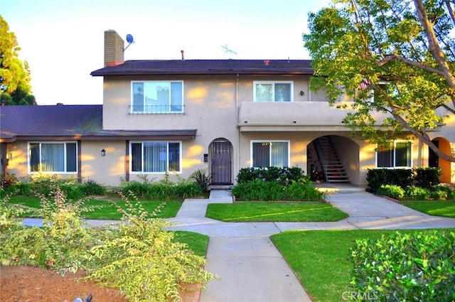 12700 Newport Ave Unit 36, Tustin, CA 92780 - view of front of house with stairs, stucco siding, a front lawn, and a chimney