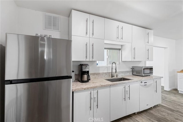 28799 Murrieta Rd, Menifee, CA 92586 - kitchen featuring appliances with stainless steel finishes, a sink, white cabinetry, light wood finished floors, and light stone countertops