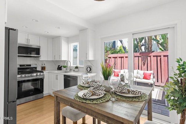 10801 Blix St Unit 2, Toluca Lake, CA 91602 - kitchen featuring stainless steel appliances, white cabinetry, light countertops, backsplash, and light wood-style floors