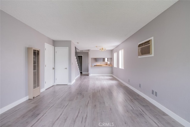 1341 N Keystone St, Burbank, CA 91506 - unfurnished living room with a wall mounted air conditioner, a heating unit, wood finished floors, a chandelier, and a textured ceiling
