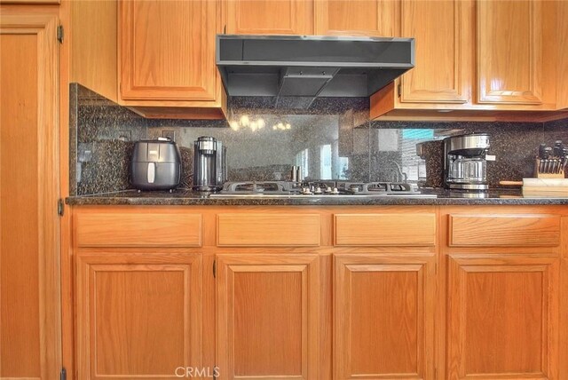 10707 Champagne Rd, Alta Loma, CA 91737 - kitchen with gas stovetop, ventilation hood, tasteful backsplash, and dark stone countertops