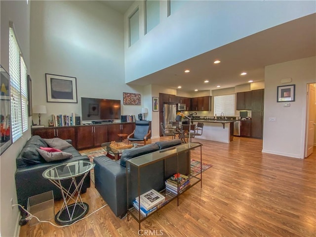 5 Abarrota St, Rancho Mission Viejo, CA 92694 - living area with light wood-style flooring, a high ceiling, baseboards, and recessed lighting