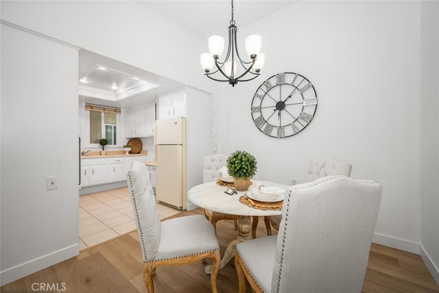13400 Del Monte Unit 1M, Seal Beach, CA 90740 - dining area featuring a chandelier, a tray ceiling, light wood-style flooring, baseboards, and crown molding