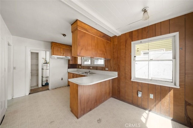 1427 Beach St, San Luis Obispo, CA 93401 - kitchen with brown cabinets, a peninsula, plenty of natural light, light countertops, and wood walls