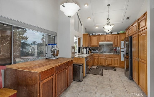 9979 Timbermist Ct, Rancho Cucamonga, CA 91737 - kitchen with under cabinet range hood, black appliances, decorative backsplash, a sink, and brown cabinetry