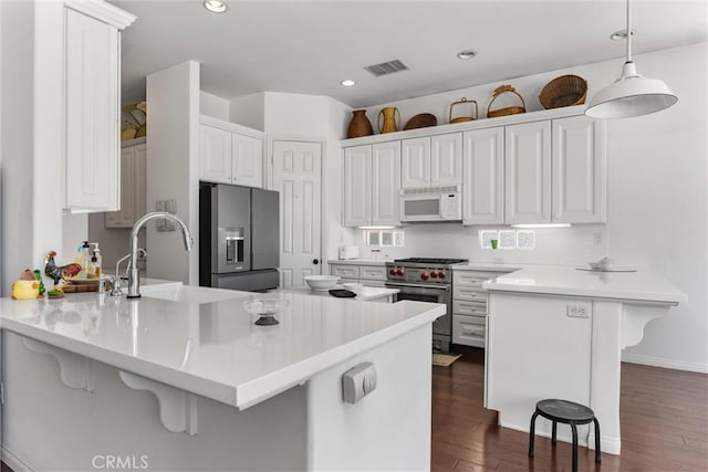2403 Crocus Dr, Bakersfield, CA 93311 - kitchen with stainless steel appliances, a peninsula, a kitchen bar, dark wood-style flooring, and recessed lighting