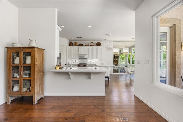 2403 Crocus Dr, Bakersfield, CA 93311 - kitchen with white microwave, a peninsula, dark wood finished floors, light countertops, and white cabinets