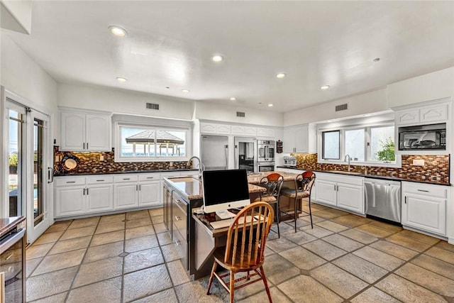 1532 Kensing Ln, North Tustin, CA 92705 - kitchen with appliances with stainless steel finishes, decorative backsplash, a breakfast bar, white cabinets, and recessed lighting