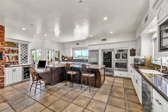1532 Kensing Ln, North Tustin, CA 92705 - kitchen featuring stainless steel appliances, backsplash, a breakfast bar, white cabinets, and recessed lighting