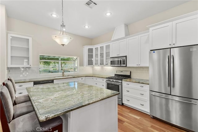 36475 Avenida La Cresta, Murrieta, CA 92562 - kitchen with appliances with stainless steel finishes, a sink, glass insert cabinets, a breakfast bar area, and white cabinetry