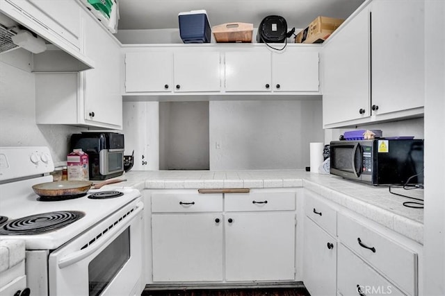 2212 Grant Ave, Redondo Beach, CA 90278 - kitchen featuring white electric range oven, black microwave, under cabinet range hood, white cabinets, and tile counters