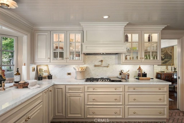 22372 Harwich Ln, Huntington Beach, CA 92646 - kitchen featuring stainless steel gas stovetop, decorative backsplash, glass insert cabinets, light stone counters, and premium range hood