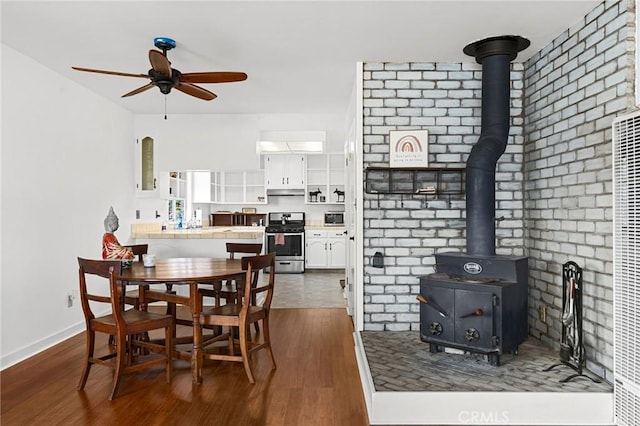 814 Natures Way, Paradise, CA 95969 - dining room featuring a wood stove, dark wood-style flooring, a ceiling fan, and baseboards