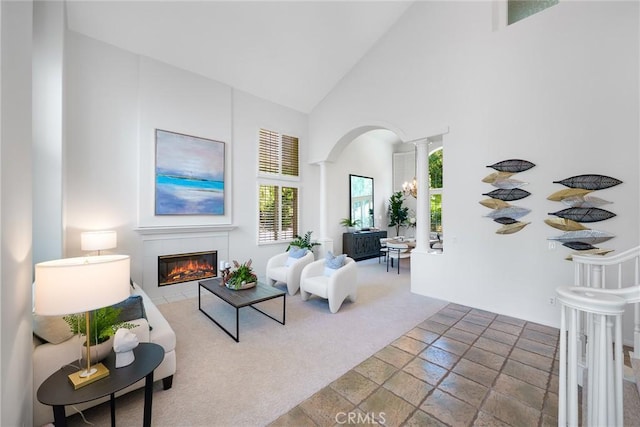 12800 N Overlook Dr, Rancho Cucamonga, CA 91739 - carpeted living area with decorative columns, arched walkways, a tile fireplace, high vaulted ceiling, and stone finish floors
