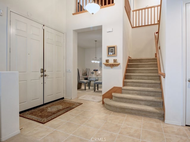 15585 Marnie Pl, Fontana, CA 92336 - foyer entrance featuring stairway, light tile patterned floors, a high ceiling, and a chandelier