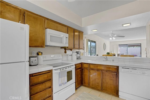 69723 Encanto Ct, Rancho Mirage, CA 92270 - kitchen with white appliances, brown cabinetry, light tile patterned floors, a sink, and ceiling fan