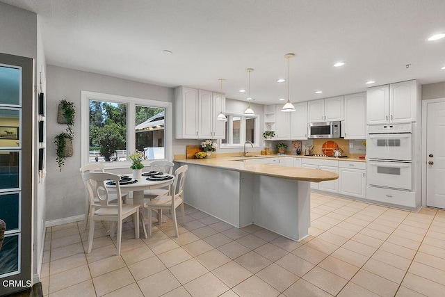 2735 Los Pinos Cir, Camarillo, CA 93012 - kitchen featuring appliances with stainless steel finishes, a peninsula, white cabinetry, light countertops, and light tile patterned floors