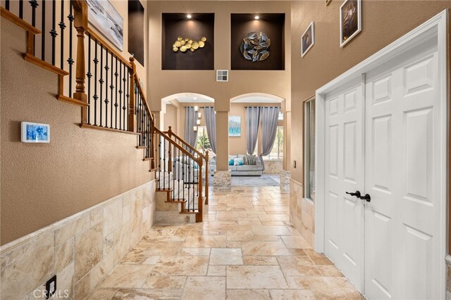 18936 Summerleaf Ln, Riverside, CA 92504 - entryway with stone tile floors, a towering ceiling, arched walkways, stairway, and a textured wall