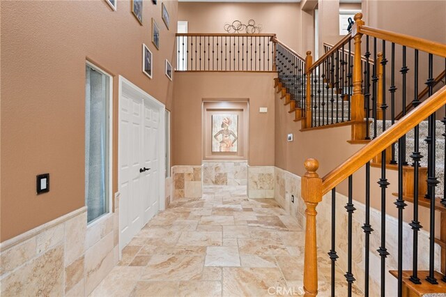 18936 Summerleaf Ln, Riverside, CA 92504 - foyer entrance featuring stone tile floors, stairway, a towering ceiling, and wainscoting