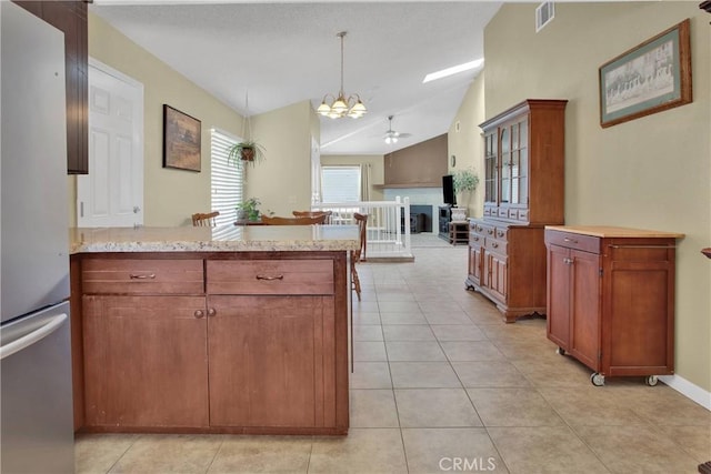 18603 Mecca St, Hesperia, CA 92345 - kitchen featuring freestanding refrigerator, a peninsula, lofted ceiling, a ceiling fan, and light stone countertops