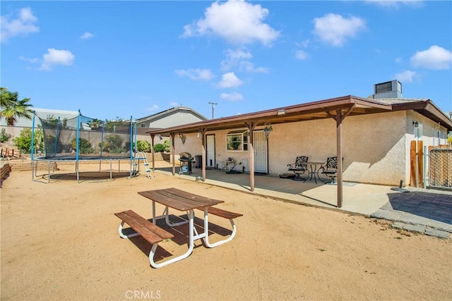 18603 Mecca St, Hesperia, CA 92345 - back of property featuring a trampoline, a patio area, stucco siding, and a chimney