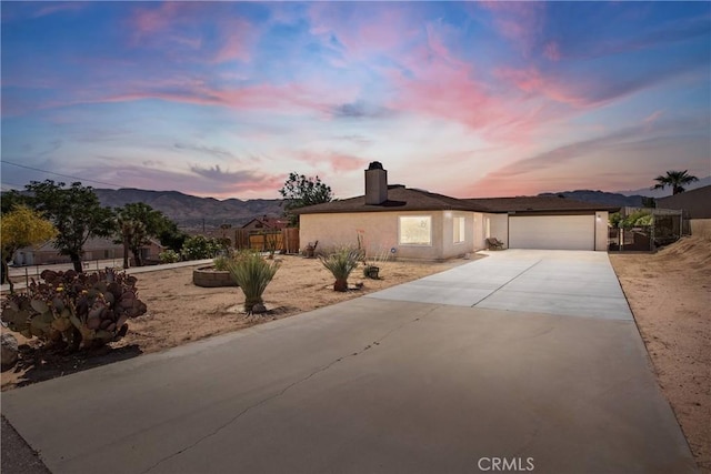 18603 Mecca St, Hesperia, CA 92345 - view of front of house featuring concrete driveway, a garage, a mountain view, a chimney, and stucco siding
