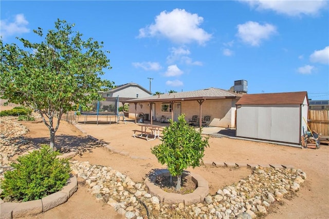 18603 Mecca St, Hesperia, CA 92345 - back of house featuring a trampoline, a patio area, cooling unit, and a chimney