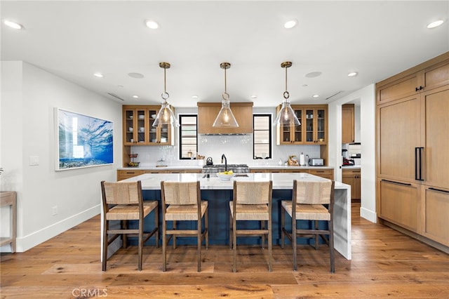 213 Avenida Princesa, San Clemente, CA 92672 - kitchen with a kitchen island with sink, light wood-style flooring, premium range hood, backsplash, and baseboards