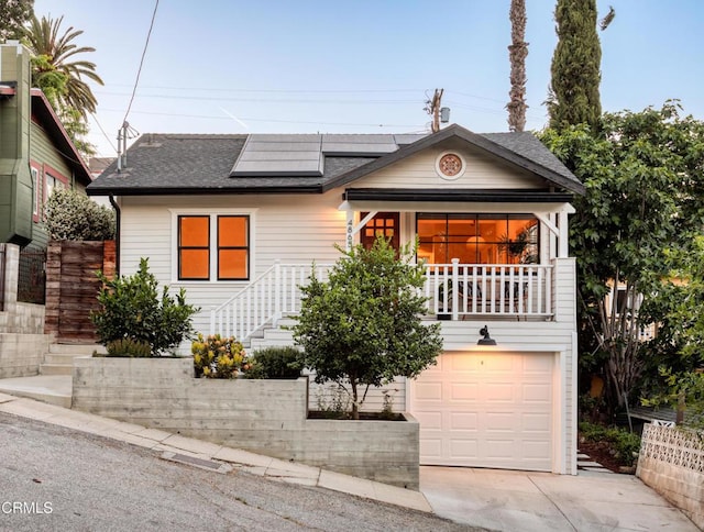 4865 Granada St, Los Angeles, CA 90042 - view of front facade with an attached garage, a shingled roof, roof mounted solar panels, concrete driveway, and stairs