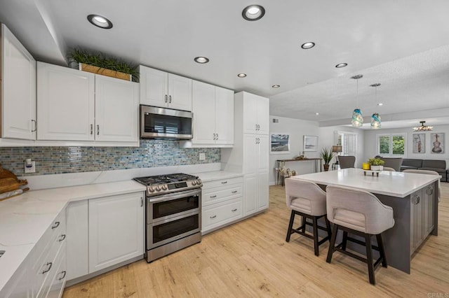 3925 Linmar Ln, Carlsbad, CA 92008 - kitchen featuring stainless steel appliances, white cabinets, a kitchen breakfast bar, open floor plan, and decorative backsplash