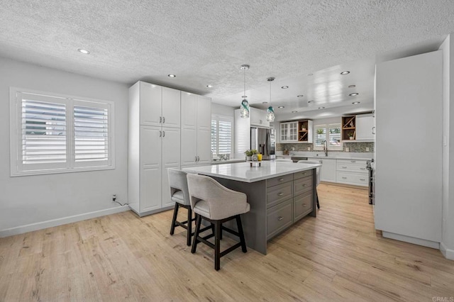 3925 Linmar Ln, Carlsbad, CA 92008 - kitchen featuring a textured ceiling, white cabinets, gray cabinetry, a kitchen island, and light wood-style flooring