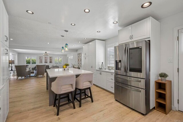 3925 Linmar Ln, Carlsbad, CA 92008 - kitchen with stainless steel fridge, white cabinets, a kitchen island, recessed lighting, and a kitchen bar