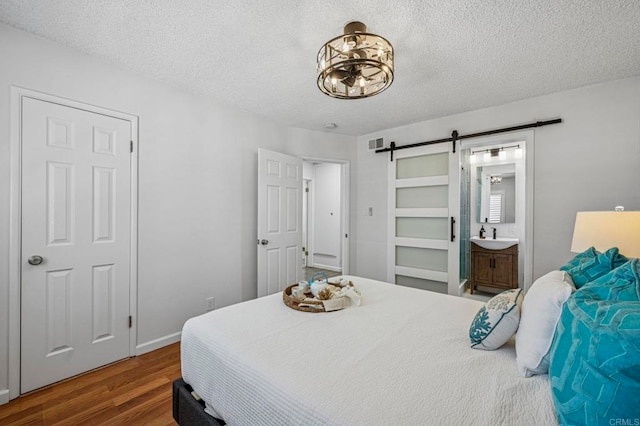 3925 Linmar Ln, Carlsbad, CA 92008 - bedroom with a barn door, wood finished floors, a textured ceiling, a chandelier, and ensuite bath
