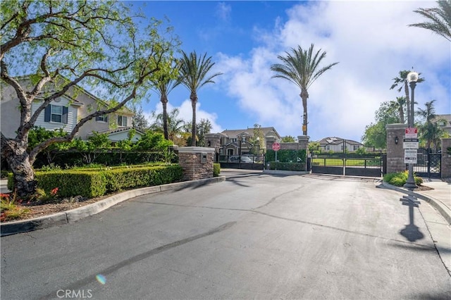 15601 N Peak Ln, Fontana, CA 92336 - view of asphalt road featuring a gate, curbs, a residential view, and a gated entry