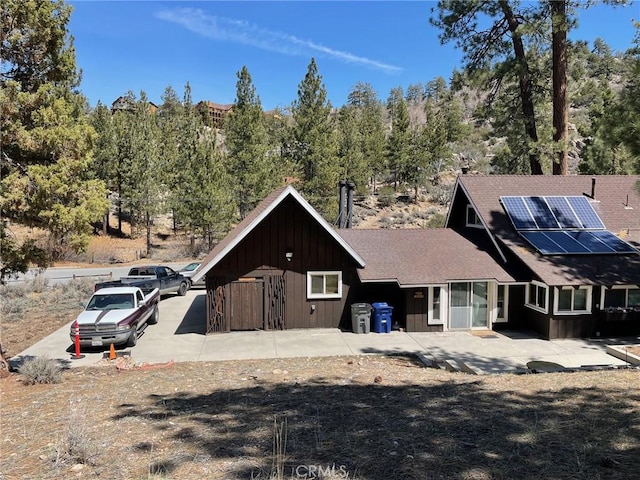 320 Starvation Flats Rd, Big Bear Lake, CA 92315 - view of front of home with board and batten siding, roof mounted solar panels, and a shingled roof