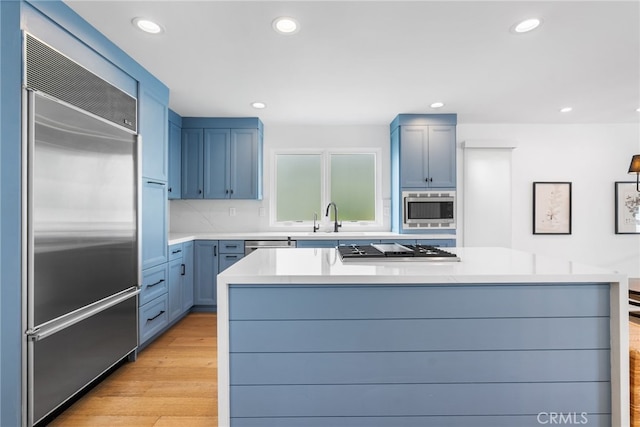 332 L St, Newport Beach, CA 92661 - kitchen with built in appliances, blue cabinetry, a sink, light countertops, and a center island