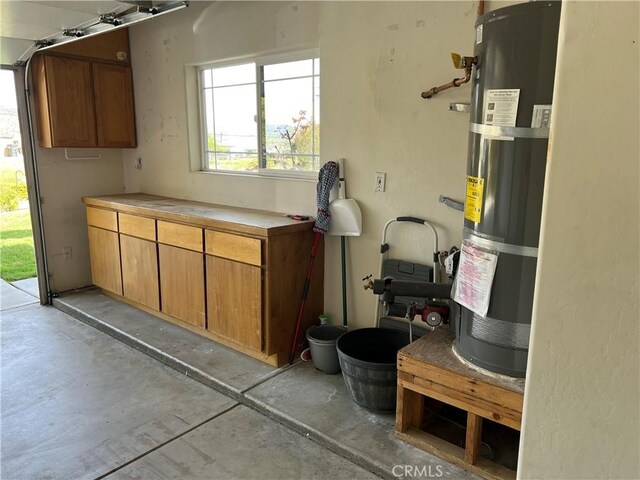 22104 Mccarthy Dr, Tehachapi, CA 93561 - kitchen with strapped water heater, unfinished concrete floors, brown cabinetry, and light countertops