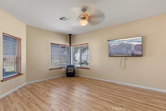 22104 Mccarthy Dr, Tehachapi, CA 93561 - unfurnished room with a wood stove, a ceiling fan, wood finished floors, and plenty of natural light