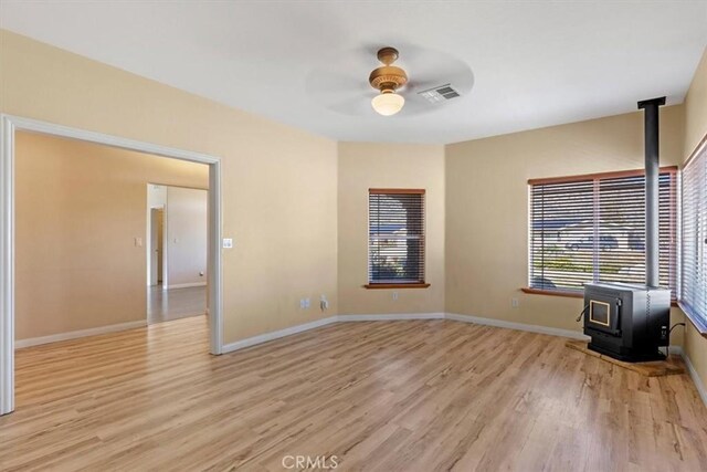 22104 Mccarthy Dr, Tehachapi, CA 93561 - unfurnished room featuring a wood stove, ceiling fan, light wood-type flooring, and baseboards