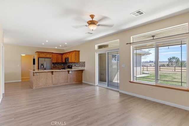 22104 Mccarthy Dr, Tehachapi, CA 93561 - kitchen with stainless steel appliances, a peninsula, baseboards, light wood-style flooring, and tasteful backsplash