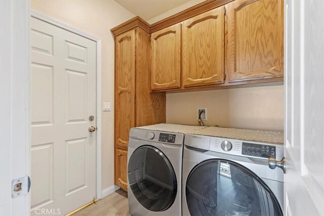 22104 Mccarthy Dr, Tehachapi, CA 93561 - washroom featuring washing machine and clothes dryer, cabinet space, and light wood-type flooring