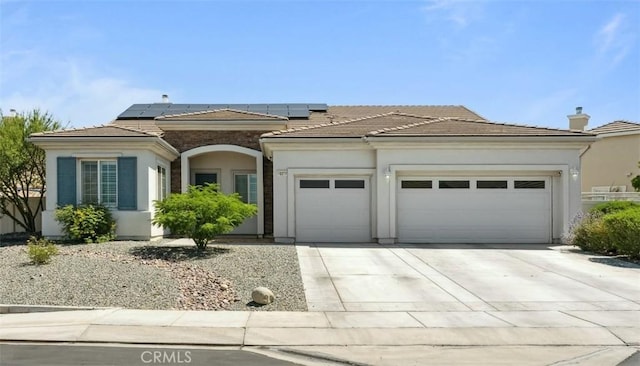 10237 Cotoneaster St, Apple Valley, CA 92308 - view of front facade featuring an attached garage, concrete driveway, roof mounted solar panels, stucco siding, and a tile roof