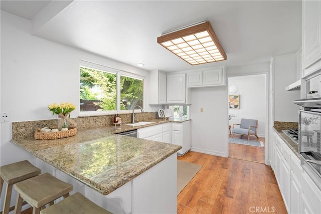 2704 Albatross Dr, Costa Mesa, CA 92626 - kitchen with a sink, a peninsula, white cabinetry, light stone counters, and light wood finished floors