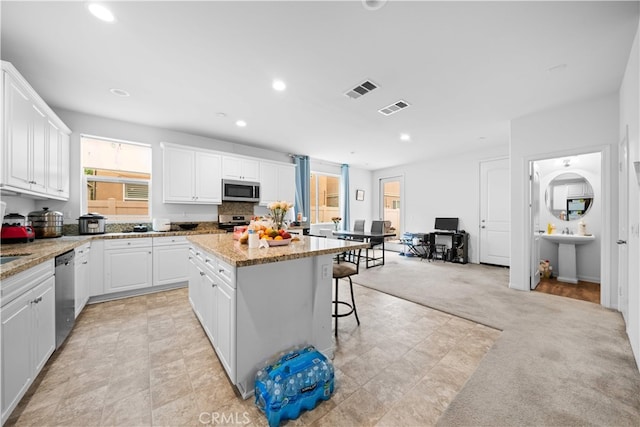 5874 Silver Oaks Dr, Chino, CA 91710 - kitchen with stainless steel appliances, a center island, white cabinetry, recessed lighting, and a breakfast bar area